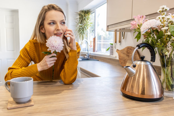 浪漫的金发美女美丽的年轻女人在厨房里与她的男朋友打电话图片下载