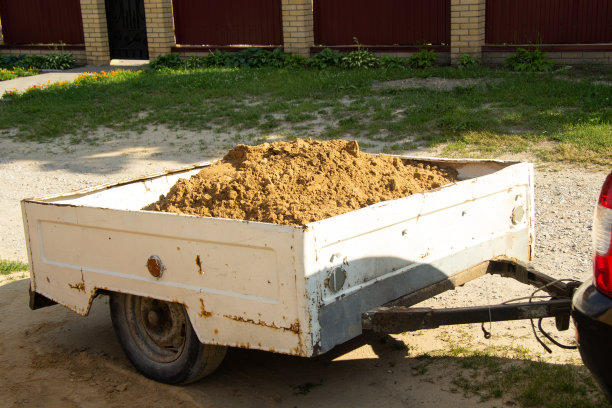 一辆旧的、生锈的拖车挂在倒沙子的汽车上。它在街上。连在车上。图片下载