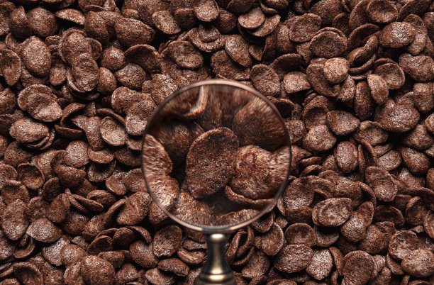 用放大镜看巧克力麦片片。可可玉米片谷物的背景图片下载