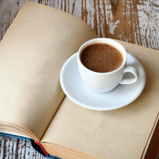 桌上放着一杯咖啡和一本书。图片下载