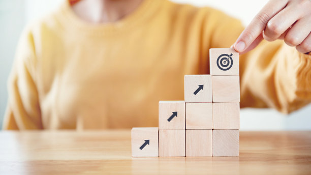 经营理念成长成功过程，女人手排木块堆叠为目标的阶梯。图片下载