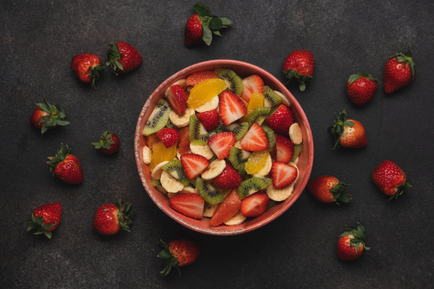 水果沙拉在粉红色的碗和棕色的背景图片下载
