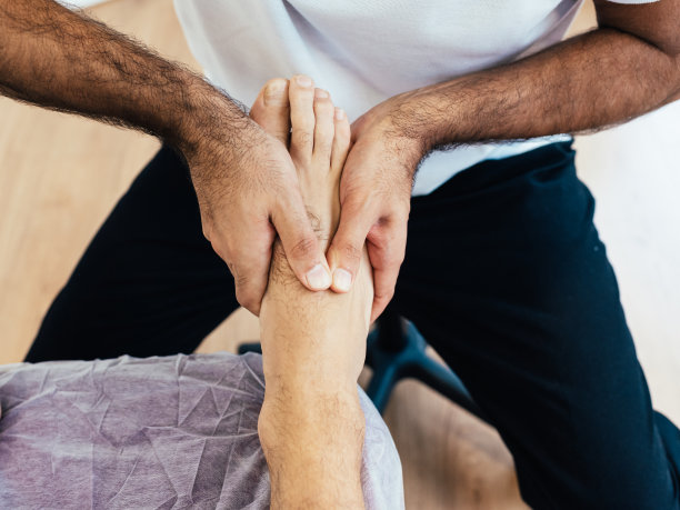 在理疗诊所里，一个脚疼的病人用医生的手治好了。足底按摩与自然疗法。健康的概念。图片下载