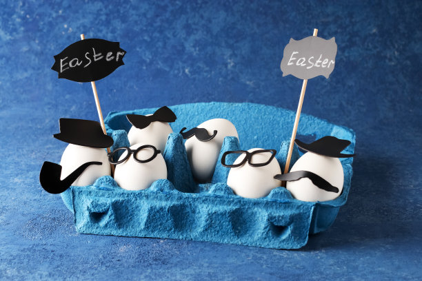 一个养鸡场的白色鸡蛋放在一个硬纸板的蓝色市场盒子里，背景是坚实的。欢乐的人物陪伴在创意的概念中度过复活节假日。图片下载