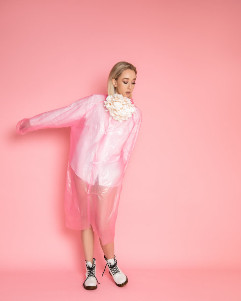 穿着雨衣的漂亮年轻女子在工作室里，粉红色的背景。完整的照片。图片下载