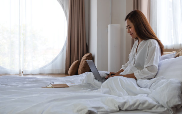 躺在家里床上用笔记本电脑工作的妇女图片下载