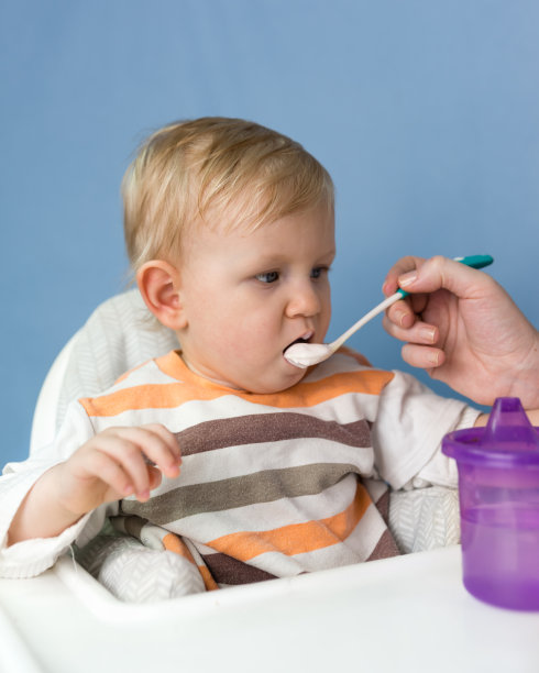 一个一岁的白发小孩用勺子喝酸奶图片下载