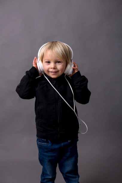 可爱的孩子，穿着黑毛衣，听着音乐的男孩图片下载