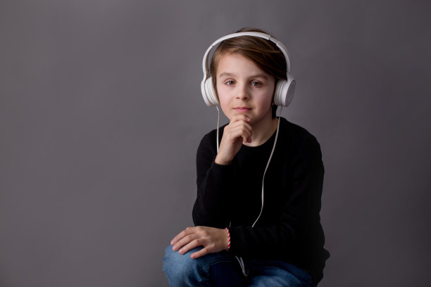 可爱的孩子，穿着黑毛衣，听着音乐的男孩图片下载