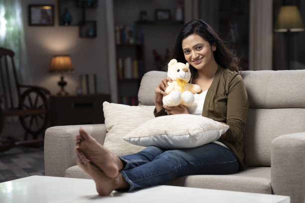 坐在沙发上抱着泰迪熊的女人:-库存照片图片下载