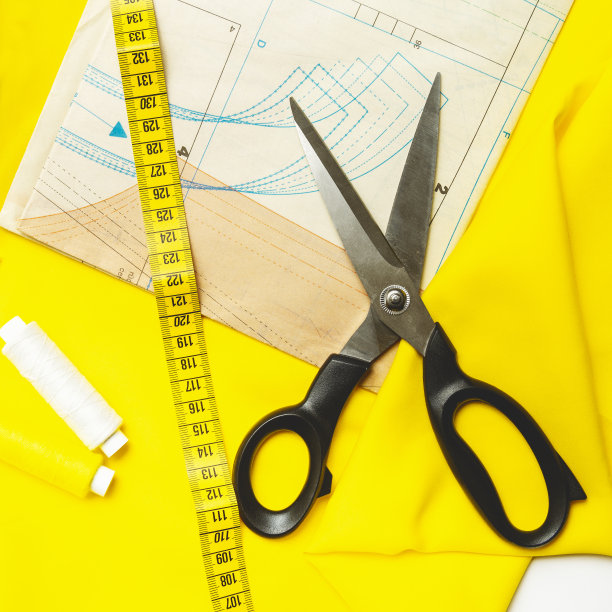 裁剪的概念。缝纫和针线活的配件。卷尺，粉笔，线和黄色织物和图案。近距离图片下载