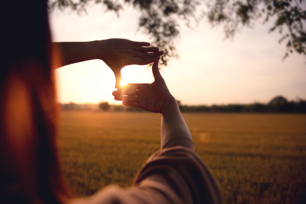 新年计划和愿景概念，女人的手做框架手势与日落的特写。图片下载