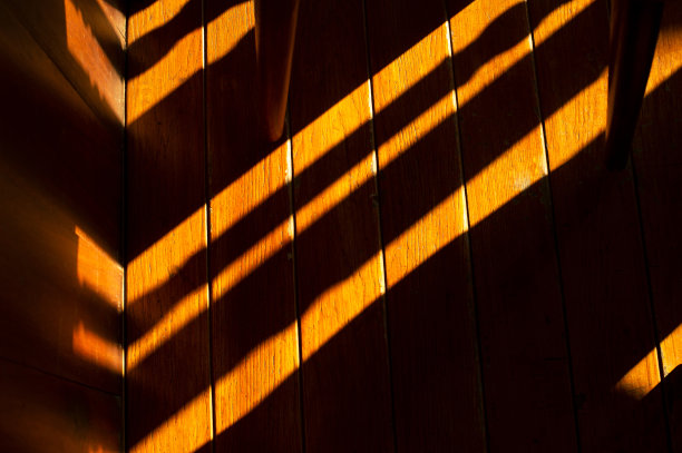 阳光和黑色阴影在橙色棕色的木地板和腿椅的室内背景细节图片下载