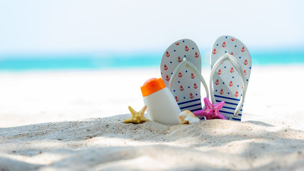 适合健康肌肤的女性用白色塑料瓶装的防晒或防晒乳液，热带海滩上的海星，度假时的夏日配饰，图片下载