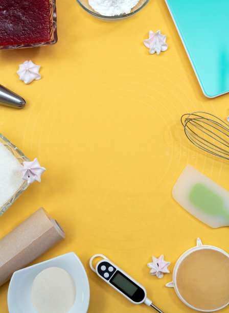 制作蛋白酥皮的工具和配料。一个温度计，一个搅拌器，一个抹刀，羊皮纸，糖，果酱，一个金属喷嘴。黄色背景和文字空间。有选择性的重点。图片下载