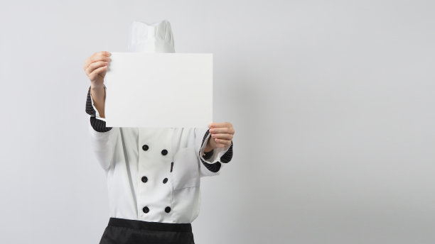 女人穿着厨师制服，拿着空白A4纸在白色的背景。图片下载