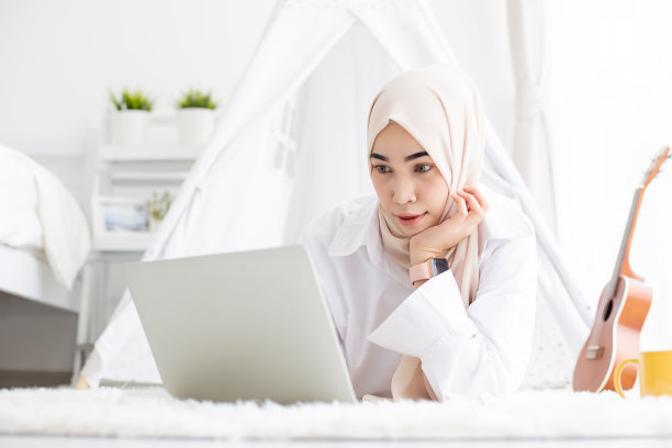 亚洲美丽的穆斯林妇女在家里用笔记本电脑工作，在家工作的概念。素材图片