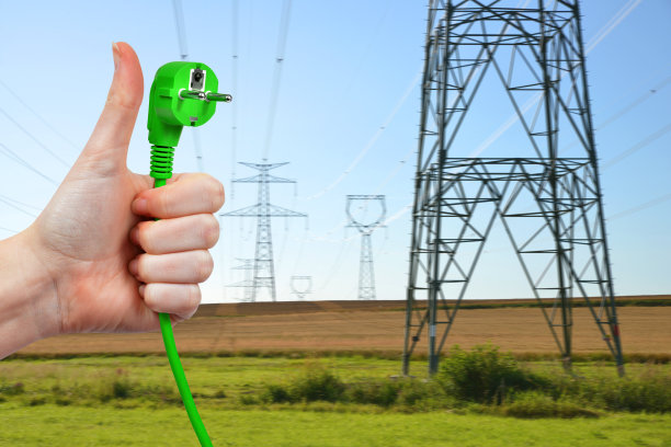 手持背景输电塔上的电插头。图片下载