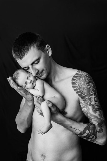 手臂上有纹身的父亲抱着黑白背景上刚出生的男婴图片下载
