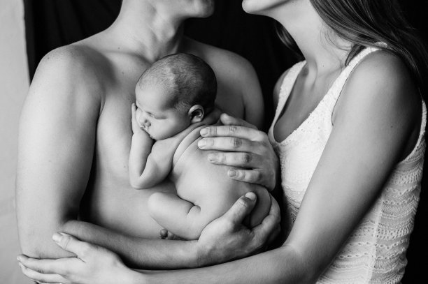 2. 妈妈和爸爸抱着他们刚出生的宝宝在拍摄新生儿照片图片下载