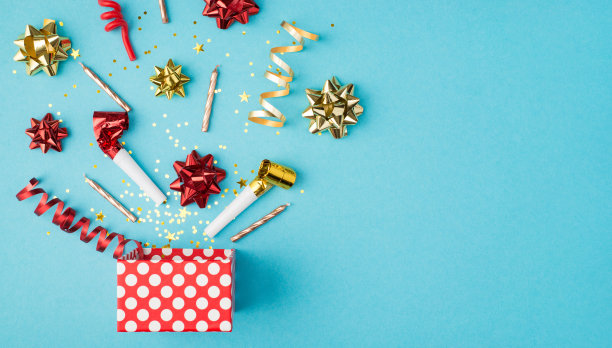 顶视图照片的生日组成爆炸的金属丝闪闪发光蛇红色黄色金色丝带星星管子和蜡烛在孤立的蓝色背景与copyspace在右边图片下载