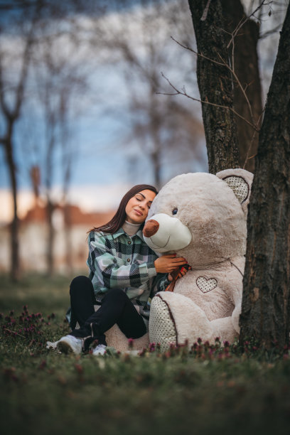 美女抱着大泰迪熊在公园里图片下载
