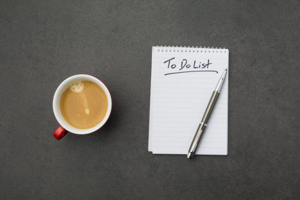 灰色书桌上的记事本和红色咖啡杯。高角度视图图片下载