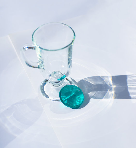 制玻璃杯。圆玻璃绿松石奖章。白色背景上透明的图案阴影。图片下载