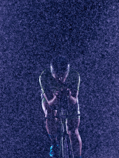 铁人三项运动员在雨夜骑自行车图片下载