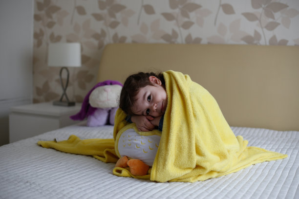 快乐的小女孩抱着玩具在床上的照片图片下载