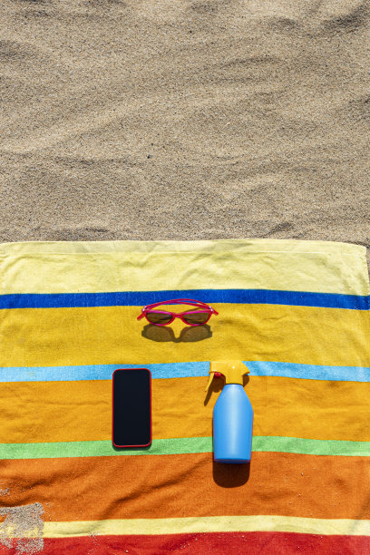 毛巾，防晒霜，太阳镜和智能手机在海滩上。夏天的概念。图片下载