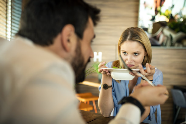 帅哥和他漂亮的金发女友正坐在餐厅享用美味佳肴。图片下载