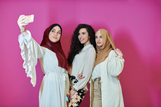 穆斯林女性用手机自拍，背景是粉色图片下载