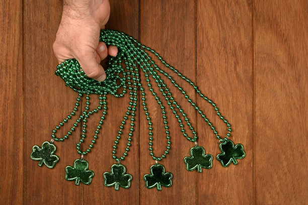 一个男人的手抓取绿色三叶草项链在木制背景图片下载