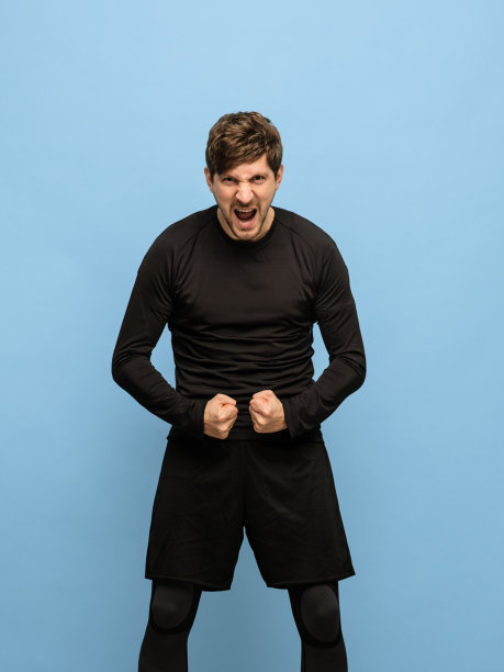 运动青年男子的肖像在蓝色背景下孤立的黑色服装。图片下载