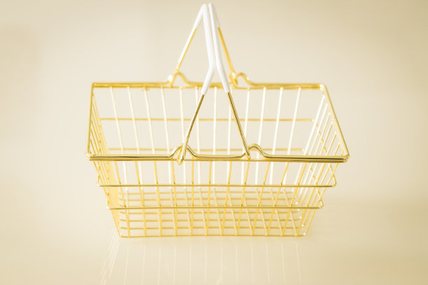 奶油色背景上放着一辆空荡荡的金色购物车图片下载