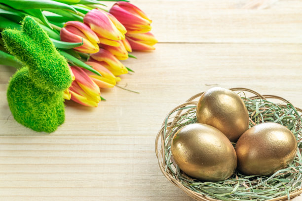 复活节金色彩蛋篮子与春天的郁金香，白色羽毛的木制背景在快乐复活节装饰。节日装饰。图片下载