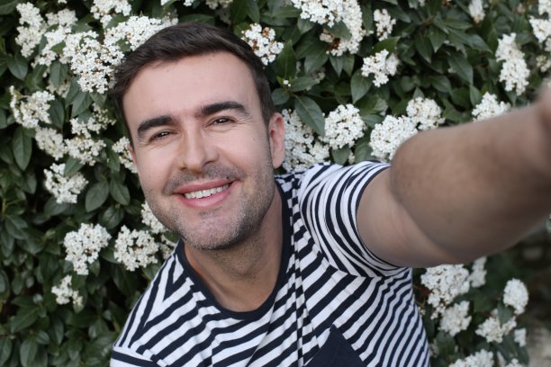 英俊的男子自拍与花卉背景图片下载
