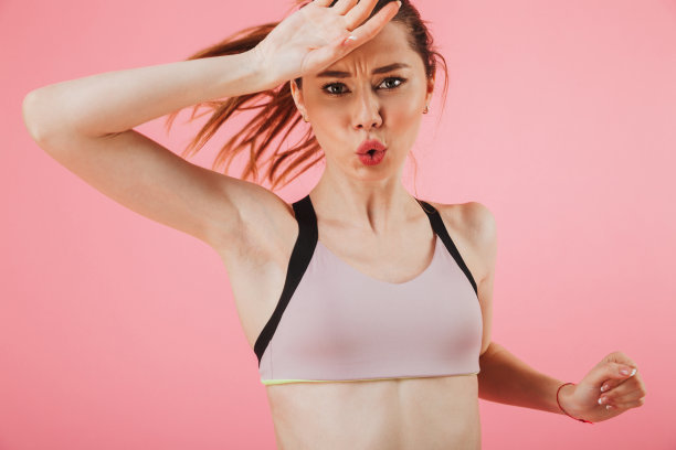 疲惫的女运动员一边跑一边擦汗图片下载