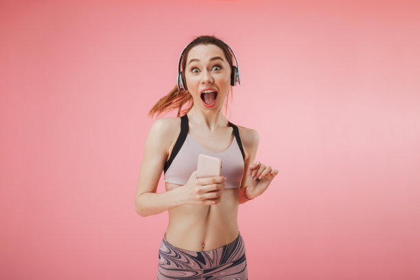 惊喜快乐的女运动员戴着耳机和智能手机跑步图片下载