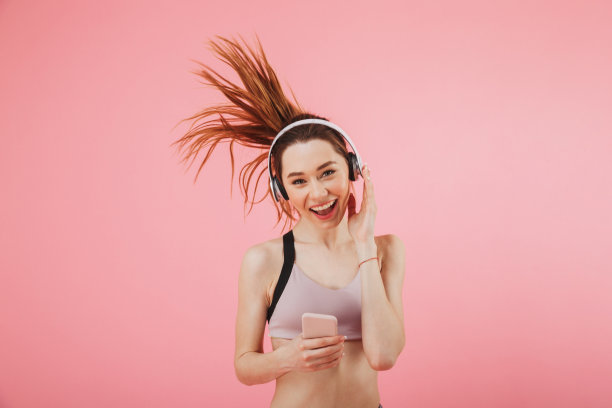 带着耳机微笑的女运动员用智能手机跑步图片下载