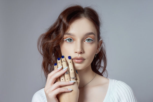 一个女人的美丽肖像与自然化妆和涂抛光指甲在她的手。戒指戴在手上图片下载