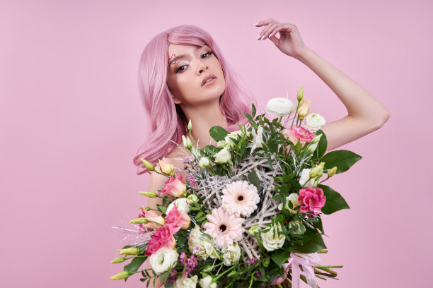 一位有着鲜艳的粉红色头发的女士手里拿着一束美丽的鲜花。自然染成美丽的妆容，发根结实图片下载