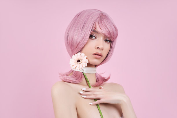 肖像性感的年轻女子粉红色的头发，美丽的花朵手中。完美的发型和染发。长着漂亮眼睛和粉红色长发的女孩图片下载