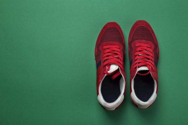 一双绿色背景的红色新球鞋。休闲的鞋子。空间的文本。图片下载