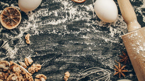 烘焙食品。新鲜食材:面粉，鸡蛋，坚果和八角，面包的橙色在黑色黑板上。烹饪平铺与复制空间。前视图。烘焙的概念。图片下载