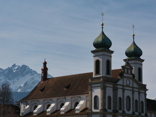 在阳光明媚的日子里，瑞士卢塞恩(Lucerne)耶稣会教堂的部分立面，屋顶上是瓦片和洋葱圆屋顶图片下载