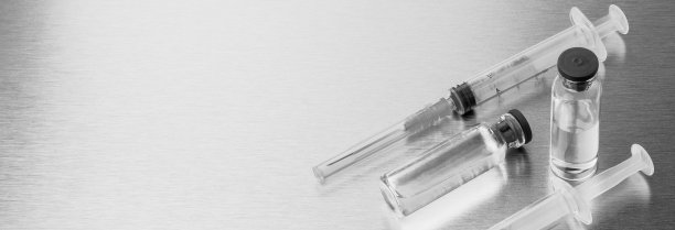 注射器和安瓿在抛光的金属背景上。黑白单色图像。副本的空间。横幅。图片下载