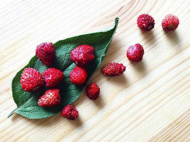 幻想的背景，鼠尾草叶与草莓在一个轻木制的背景。极简主义。图片下载