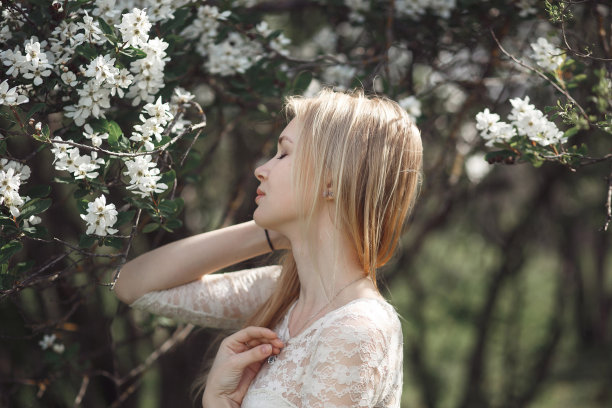 春天美丽浪漫的女孩，金发碧眼，在阳光明媚的日子里享受着盛开的苹果树图片下载